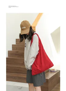 Slouchy red drawstring underarm bag shown in a lifestyle indoor setting