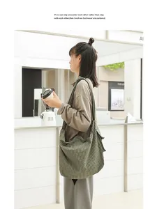 Detail of a Japanese style green checkered canvas crossbody bag on an Asian model