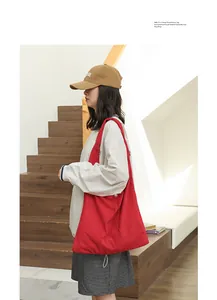 Large stylish red suede shoulder bag with drawstring design worn by a female model