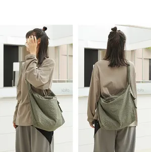 Detailed rear view of a casual green plaid nylon crossbody bag worn by a female model