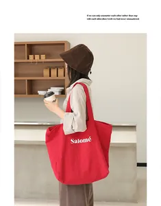 Large red linen tote bag with artistic letter print shown in a lifestyle cafe setting