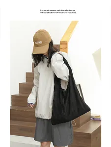 Fashionable black suede shoulder bag with drawstring pleated design in lifestyle setting.