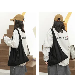 Detailed view of the black suede drawstring shoulder bag shown on a model's side and back