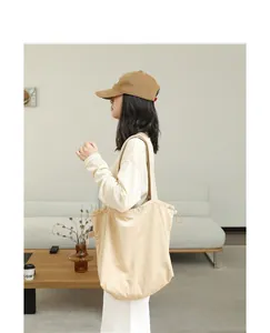 Detailed side view of a minimalist beige suede tote bag carried by a model