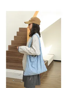 Light blue suede drawstring shoulder bag shown in a casual indoor lifestyle setting