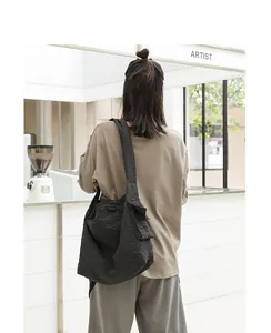 Rear view of a model wearing a black and white grid nylon messenger bag in a cafe
