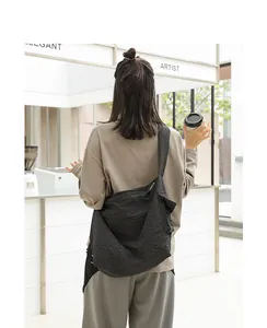 Casual black and white checkered nylon messenger bag shown on a model in a café setting