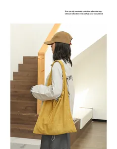 Detail view of mustard yellow suede shoulder bag with drawstring closure on model