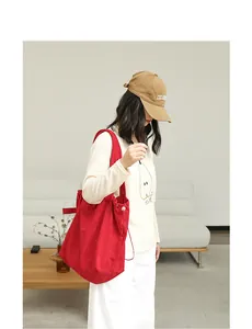 Detailed view of a vibrant red drawstring suede tote bag carried by a model.