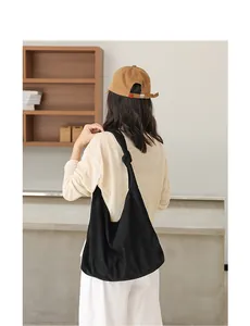 Modella con borsa hobo in camoscio nero con dettaglio nodo in un ambiente minimalista