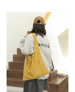 Yellow suede drawstring shoulder bag shown in a lifestyle street style photo view