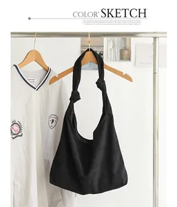 Dettaglio di una borsa hobo in pelle scamosciata nera con tracolla a nodo elegante.