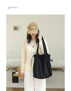 Model carrying a black pleated suede drawstring tote bag in a bright minimalist setting