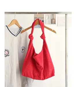 Macro vista dettagliata di una borsa hobo in finto camoscio rosso con tracolla annodata