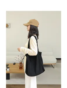 Woman carrying a black suede cloth drawstring tote bag in a minimalist interior setting