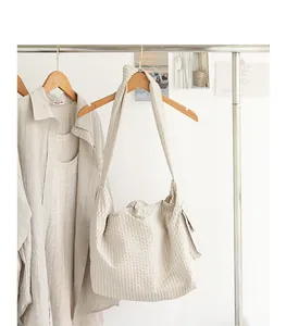 Detail view of a beige checkered Japanese style messenger bag with knotted strap hanging