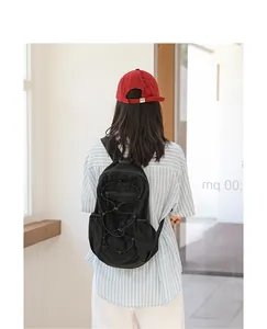 Model wearing a black casual nylon backpack with drawstring details in a minimalist setting