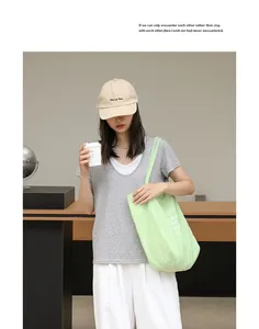Detalle de estilo de vida de un bolso tote de nailon verde menta con estampado de corazón.