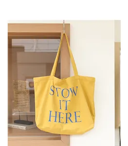 Dettaglio della borsa tote in tela gialla con stampa a lettere blu dal design casual