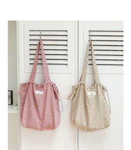 Bolsos tote de lona con lunares estilo japonés y cordón colgados en pared blanca