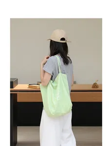 Vista trasera de una modelo con un bolso tote de nailon verde claro con estampado de corazón