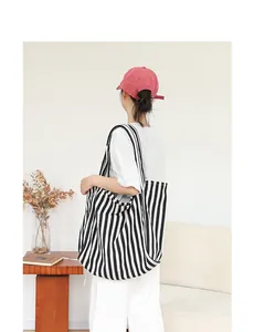 Elegante bolso tote de lona con rayas verticales blancas y negras llevado por una modelo