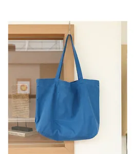 Grande borsa tote in tela blu appesa a un gancio in un ambiente dallo stile minimalista