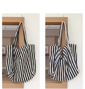 Vista detallada de elegantes bolsos de lona a rayas en negro y azul marino colgados