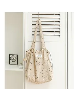 Primer plano de bolso tote de lona beige con lunares negros y cierre de cordón