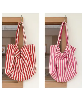Vista detallada de bolsos tote grandes de lona con rayas rojas y rosas de moda actual