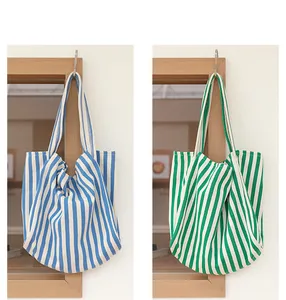 Detalle de dos bolsos tote de lona a rayas azules y verdes colgados en ganchos de madera