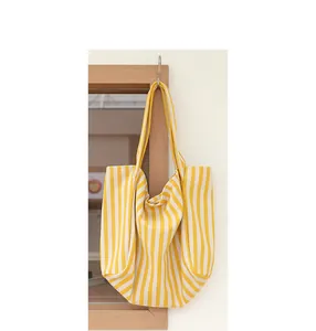 Bolso de lona a rayas amarillas y blancas colgado en un marco de madera de estilo nórdico