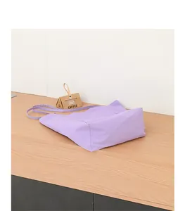 Bolso tote de nylon informal color lila claro con correas sobre un mostrador de madera