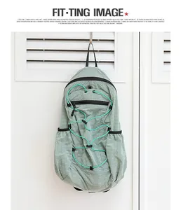 Detail of a mint green grid nylon backpack with decorative elastic cords hanging on a door.