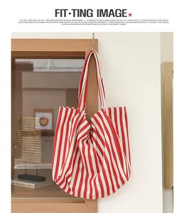 Bolso tote grande de lona a rayas rojas y blancas colgado en ambiente minimalista