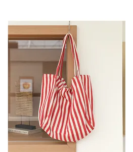 Bolso tote de lona con rayas verticales rojas y blancas colgado en un marco de madera