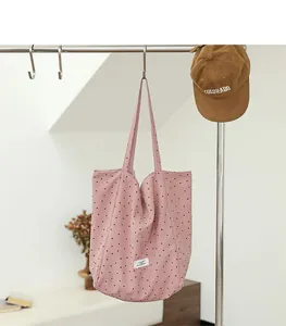 Detailed view of a pink nylon tote bag featuring a classic black polka dot pattern design