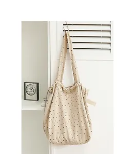 Detalle de un bolso de lona beige con lunares colgado en un gancho de pared
