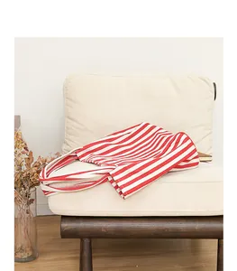 Bolso tote de lona a rayas rojas y blancas en un acogedor sofá elegante de color blanco