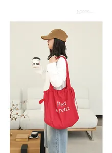 Bolso de hombro de lino rojo con cordón e impreso 'Petit à petit' usado por modelo
