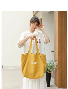 Detail of yellow linen tote bag with Salomé print carried by a model in a lifestyle setting.