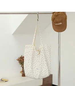 Minimalist white Japanese style tote bag with black polka dots hanging on a clothing rack