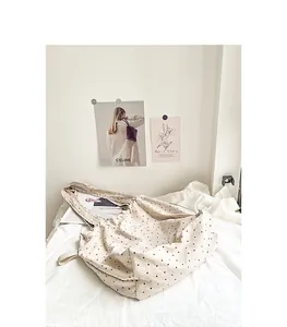 Detalle del bolso tote de lona beige con lunares y cierre de cordón en entorno de vida