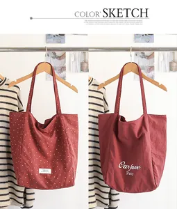 Macro view of red polka dot and letter print nylon tote bags hanging on a rack