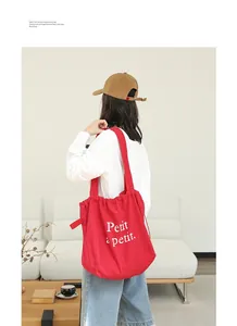 Bolso tote de lona roja con cordón y letras blancas en un entorno de estilo de vida