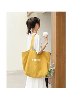 Close-up detail of a yellow linen tote bag with Salomé lettering on a model
