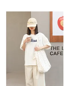 Stilvolle weiße Canvas-Tragetasche mit Punkten, getragen von einem Modell für einen Look.