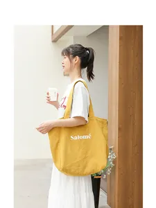 Artistic yellow linen tote bag with Salomé letter print shown in a lifestyle street scene