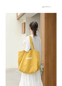 Yellow canvas tote bag with Salomé print carried by a model in a minimalist setting.