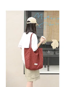 Minimalist red polka dot tote bag shown in a lifestyle context on a model's shoulder.